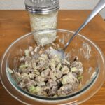 Beef salad in bowl with cheese in jar at back